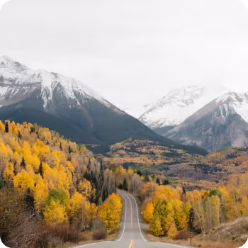 An empty road surrounded by snowy mountains