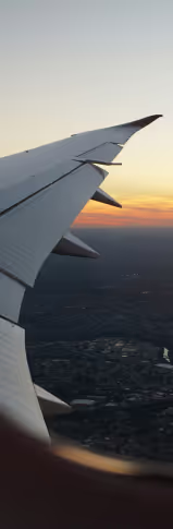 A wing of a plane and a sunset in the background